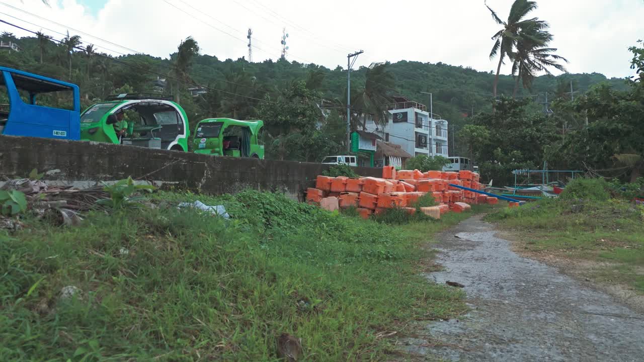 Rainy day aerial descent in Boracay, Philippines showing coastal road, palm trees, fishing boats, and hillside houses. Perfect for travel, weather, and cinematic storytelling