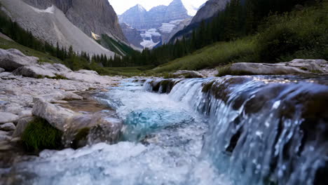 a pristine mountain river flowing through a rocky valley with distant snow-capped peaks