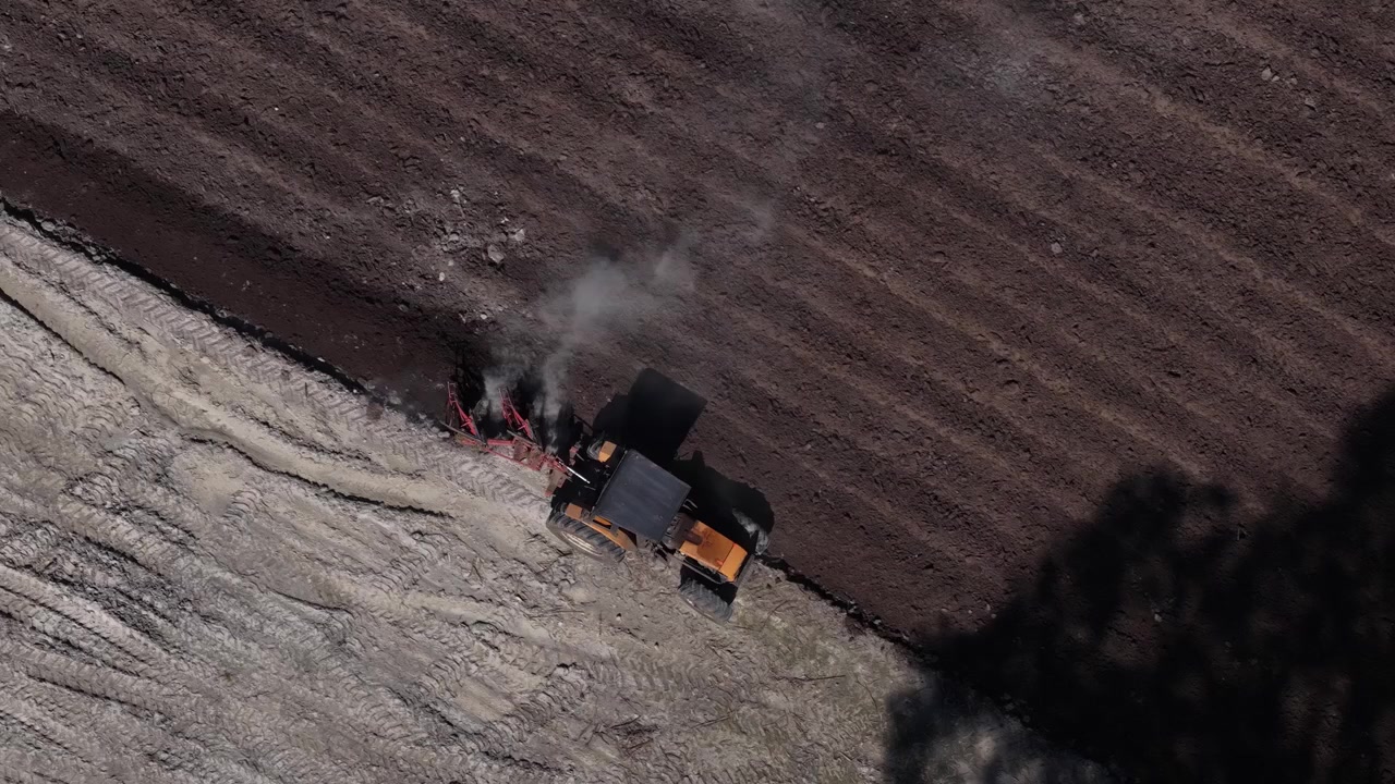 Vue par drone d'un tracteur labourant un champ agricole pour préparer la saison de croissance printanière et l'application d'engrais.
