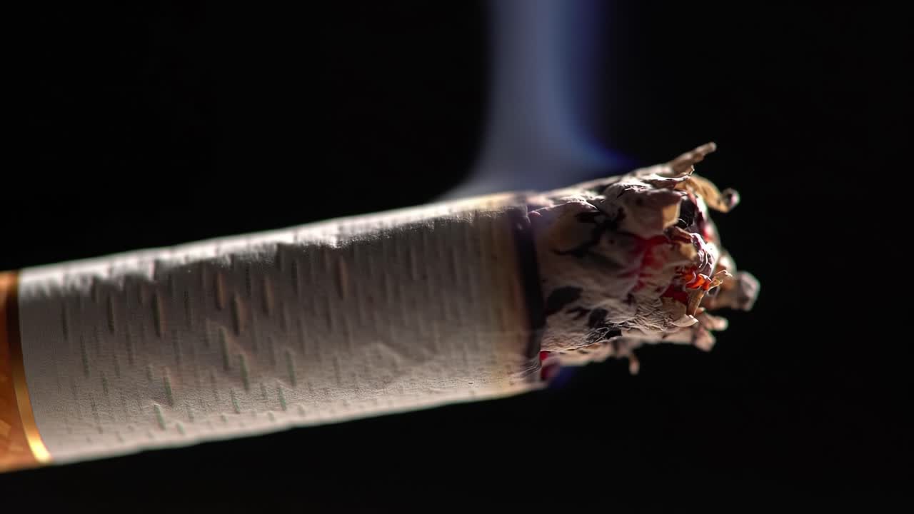 Cigarette Burning Close-Up Captured in Dark Setting Showcasing Glowing Ash