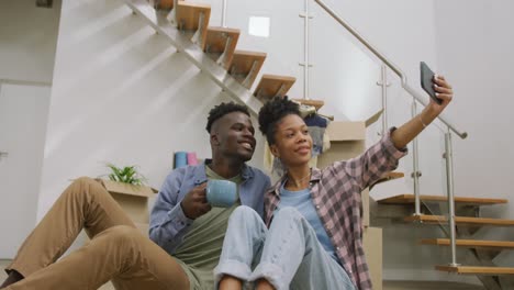 Video-of-happy-african-american-couple-taking-selfie-after-moving-into-new-house