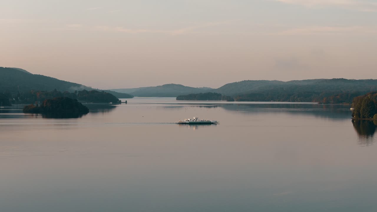 Aerial of Windermere Lake ferry in Lake District with an ascending approaching to boat and reflection in water on misty day