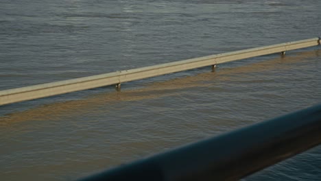 submerged guardrail in flooded river, calm water surface reflecting light, budapest, hungary