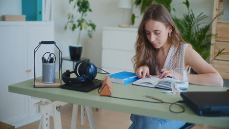 Mujer-Positiva-Estudiando-Y-Leyendo-Un-Libro-En-El-Escritorio-De-Casa