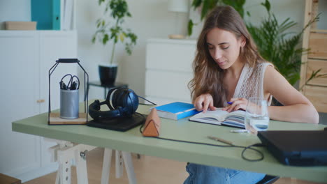 mujer positiva estudiando y leyendo un libro en el escritorio de casa
