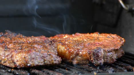 a juicy rib eye steak sitting on a grill with a small orange flame next to the meat cooking