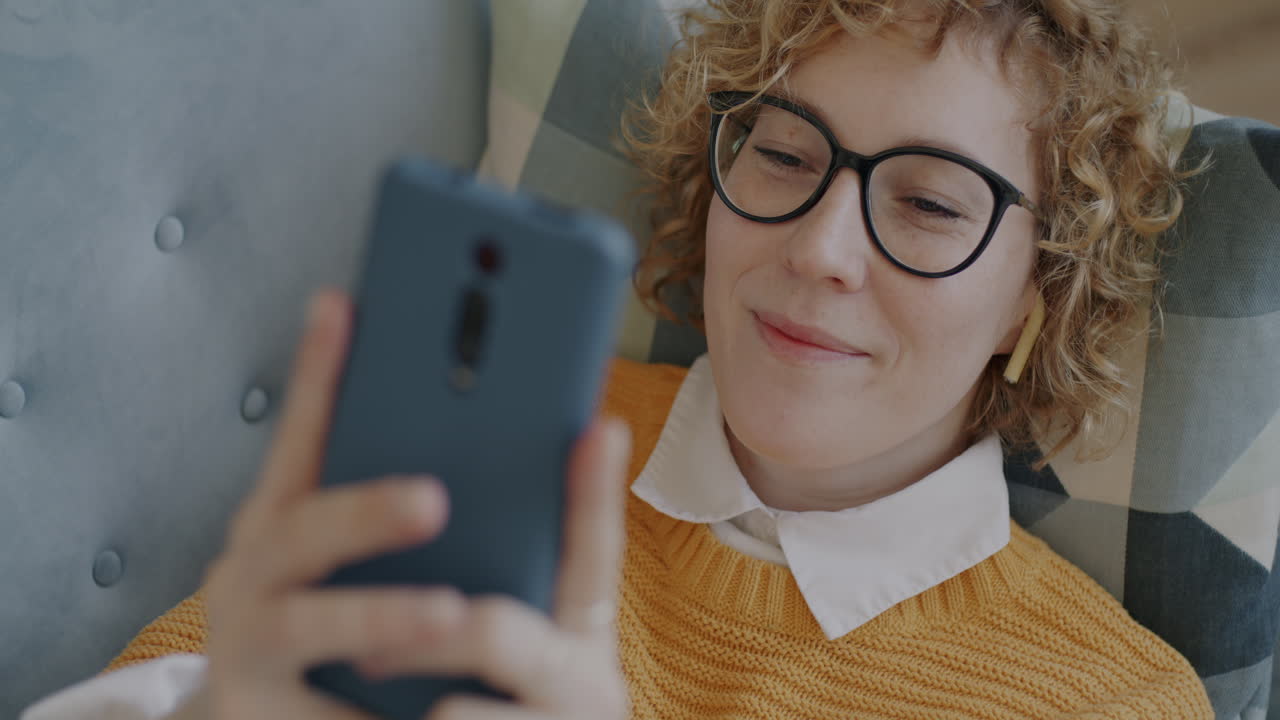 mujer relajándose en el sofá y usando el teléfono