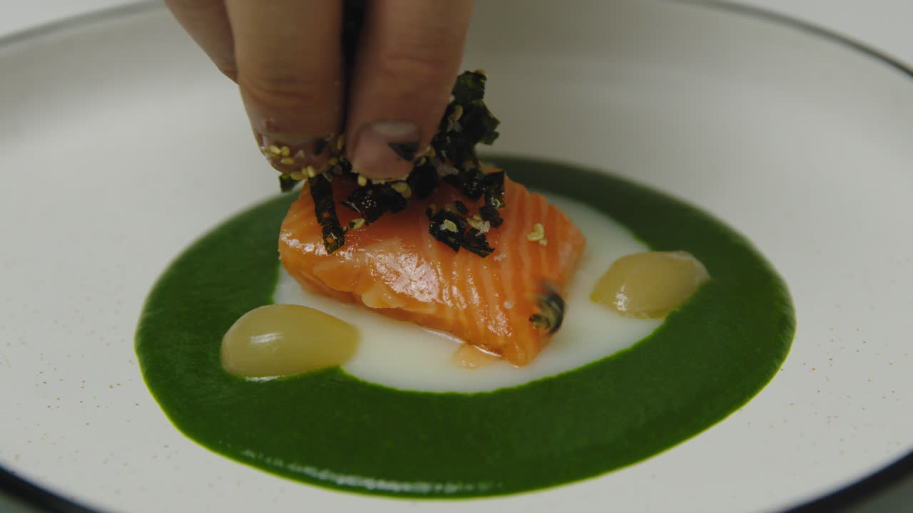 Male Chef dress salmon meal with fresh seaweed on plate,close up