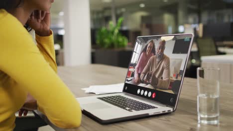 Biracial-woman-using-laptop-for-video-call,-with-diverse-business-colleagues-on-screen