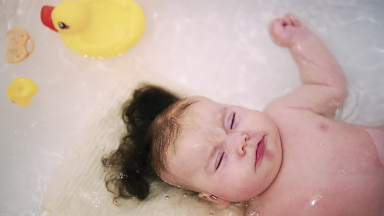 Baby enjoying bath time while being supported by a caregiver