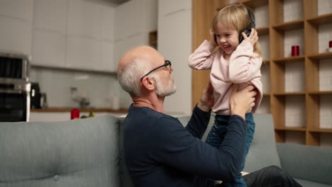 Girl-dancing-at-home-with-her-grandpa-while-listening-to-music-on-headphones