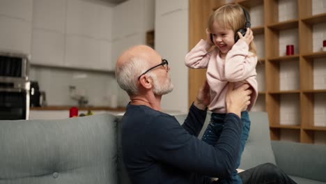 niña bailando en casa con su abuelo mientras escucha música en los auriculares
