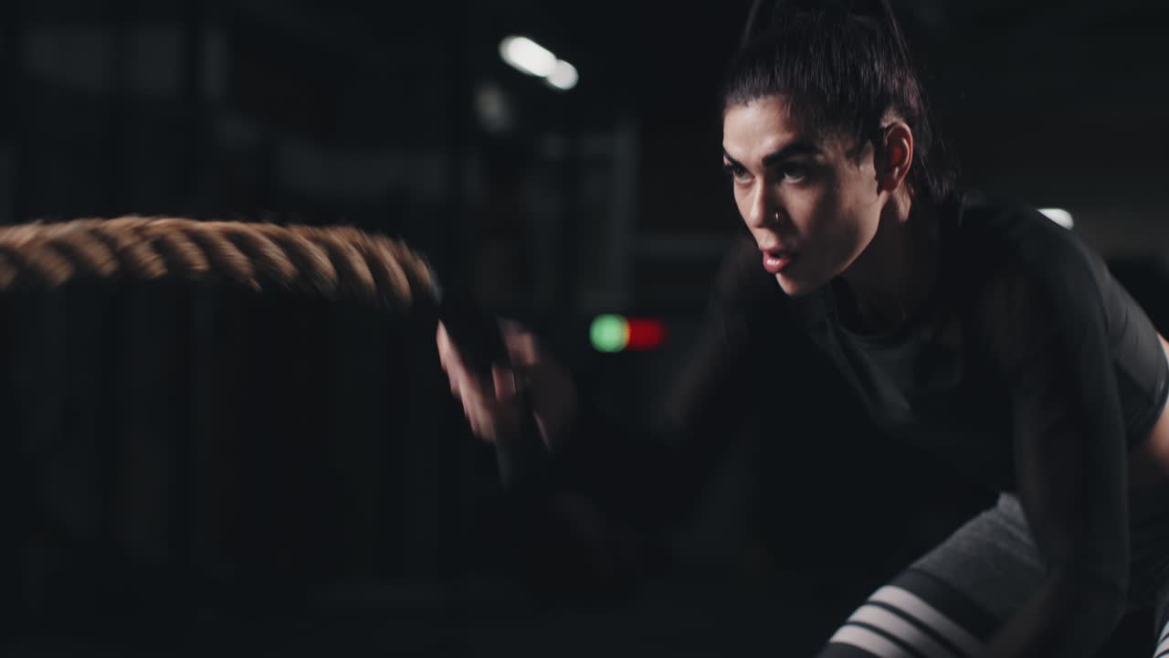 체육관에서 전투 로프로 훈련하는 젊은 여성