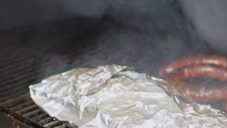 man opening bbq pit and flipping smoking sausages with tongs slow motion