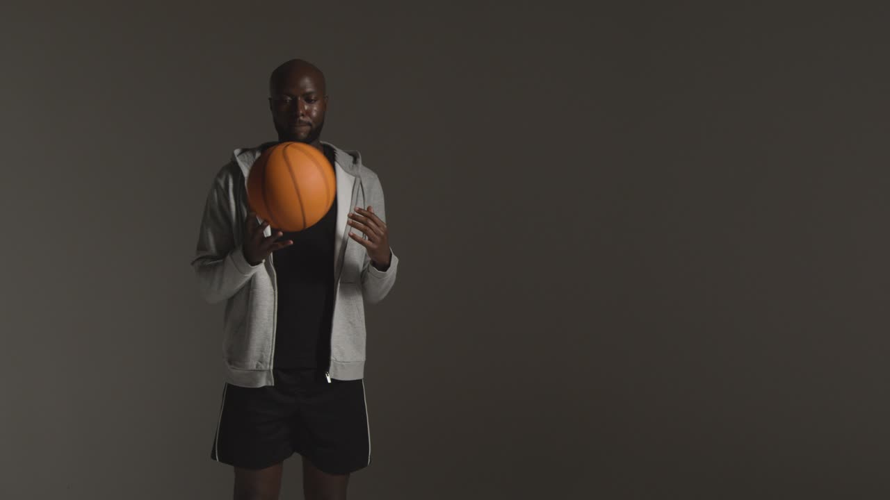 retrato de estudio de un jugador de baloncesto masculino lanzando la pelota de mano en mano contra un fondo oscuro 2
