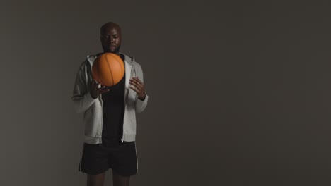 Studioporträtaufnahme-Eines-Männlichen-Basketballspielers,-Der-Vor-Dunklem-Hintergrund-Den-Ball-Von-Hand-Zu-Hand-Wirft-2