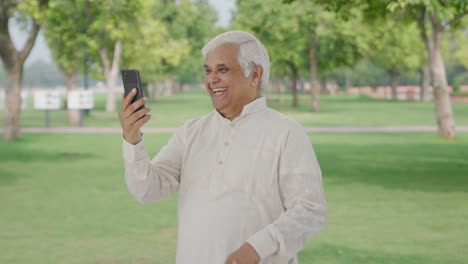 Happy-Indian-old-man-talking-on-video-call-in-park