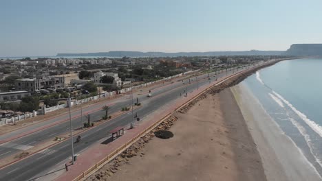 Dolly-Aéreo-Junto-A-Marine-Drive-Junto-A-La-Costa-De-La-Playa-En-Gwadar-Con-Tráfico-Pasando