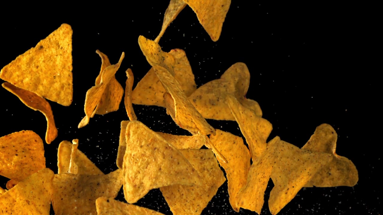 Nachos dorati che cadono con condimento su sfondo nero