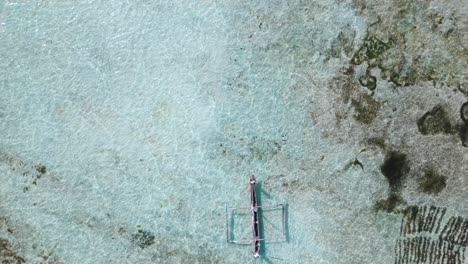 Aerial-view-of-a-poor-fisherman-with-a-torn-shirt-sails-on-a-small-boat-on-clear-blue-water-along-a-tropical-beach-with-beautiful-hotels-in-Africa