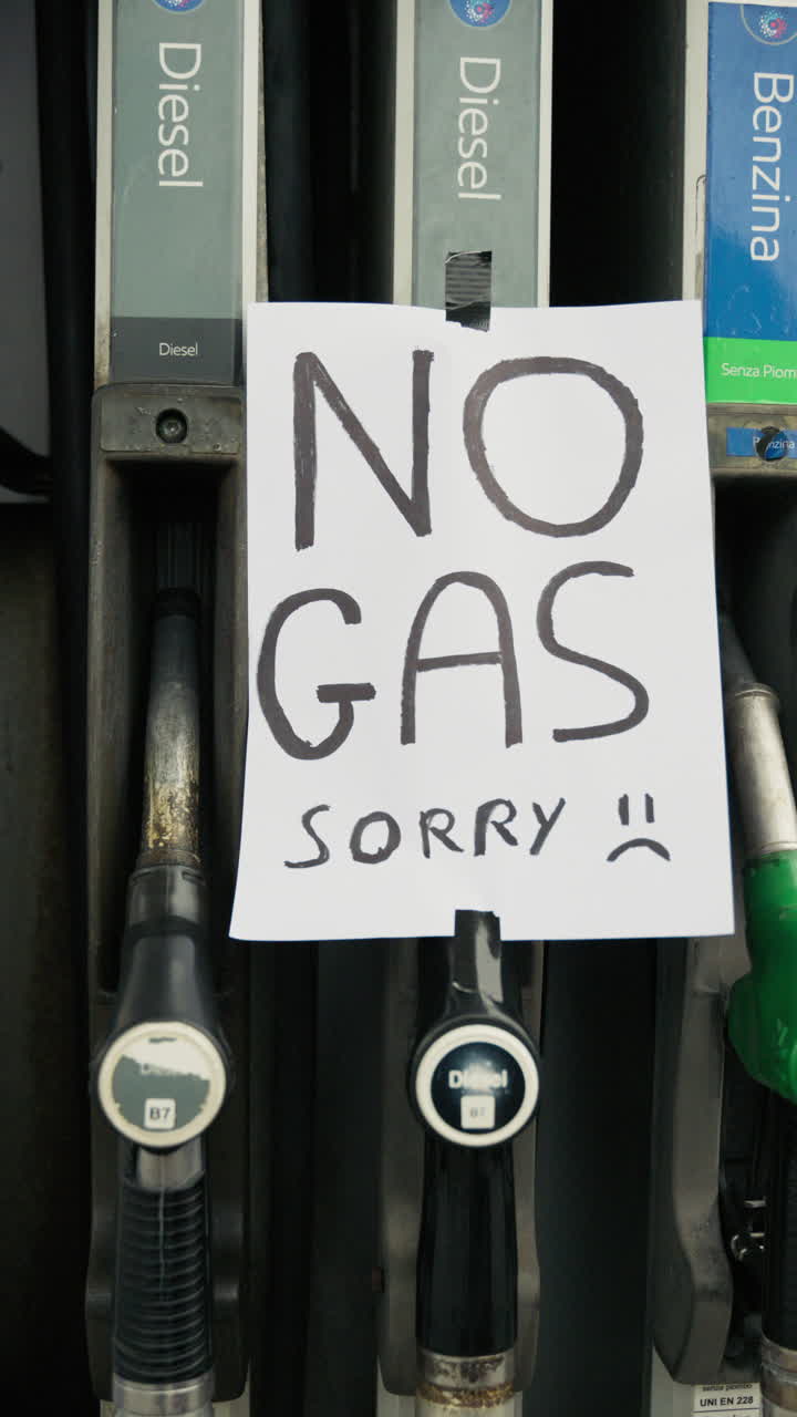 Hands Attaching 'No Gas Sorry' Sign to Fuel Pump at Gas Station