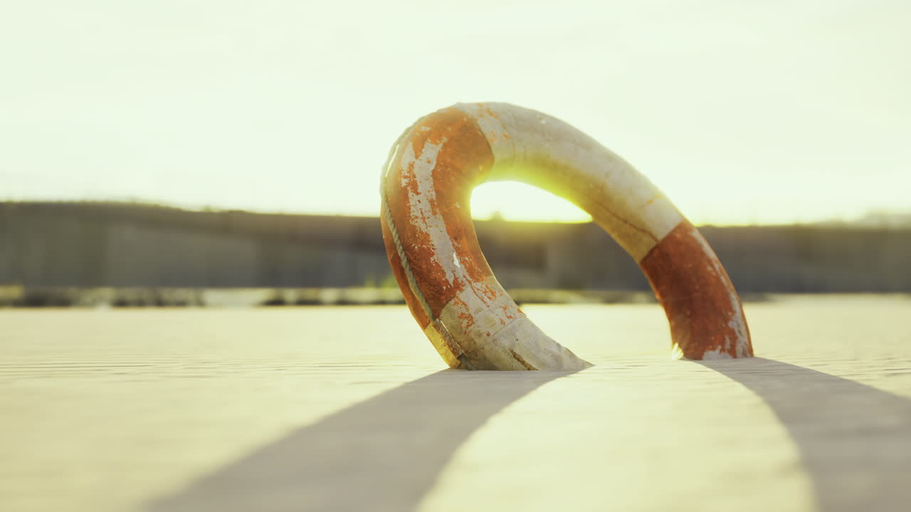 Lifebuoy resting on sandy shore during golden hour light