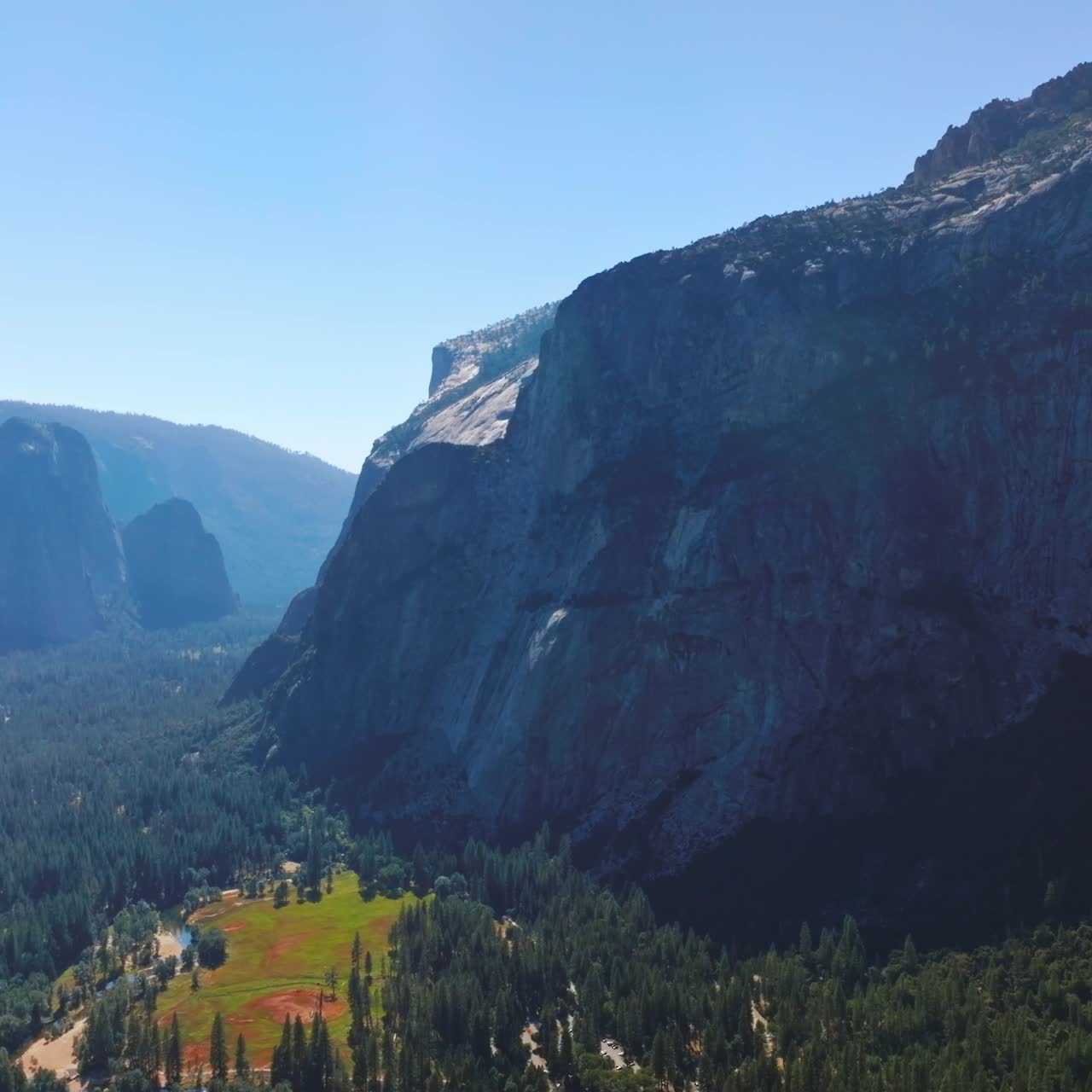 Sunlit pine tree forest surrounded by powerful rocks. National Park of Yosemite, California, USA from aerial view