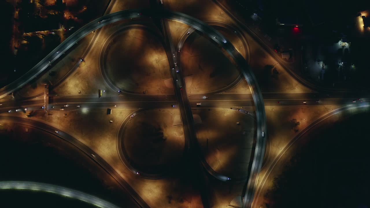 Large roundabout or road transport junction at night with car traffic, aerial top view