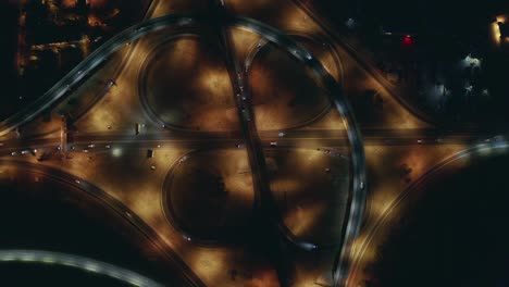 large roundabout or road transport junction at night with car traffic, aerial top view
