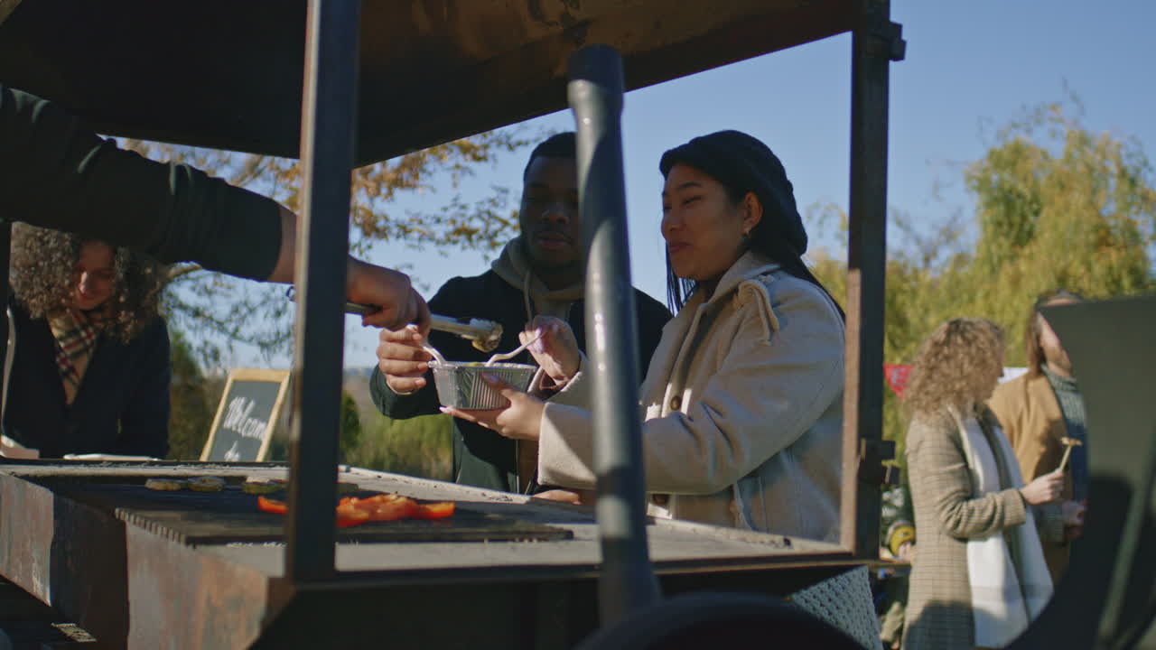 Multi Ethnic Family Trying Food Cooked on Grill Multi Ethnic Family Trying Food Cooked on Grill Adult Man Takes off Ready to Eat Vegetables and put a Portion on Plate Weekend on Local Farmers Market