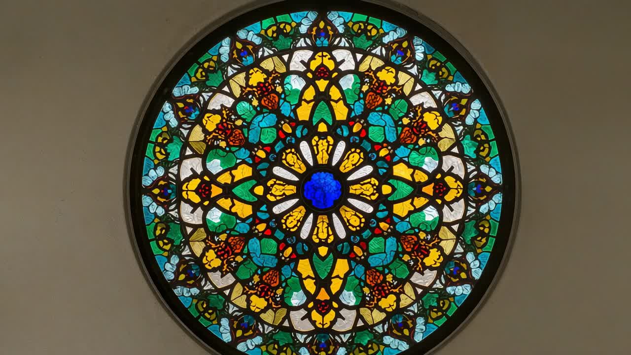 Light filtering through stained glass window with dark frame in church hall, showing radial design
