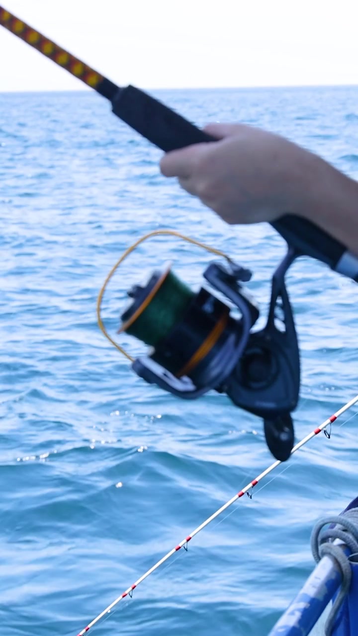 Una persona che pesca da una barca a Phuket, Thailandia, mostrando viste serene sull'oceano e un'azione di pesca concentrata.