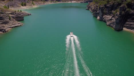 motor boat moves along a green river between rocky cliffs at summer daytime