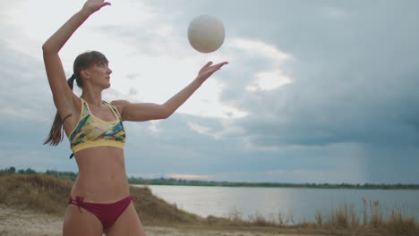 sportswoman is serving ball on open court of beach volleyball at summer day women are playing volleyball