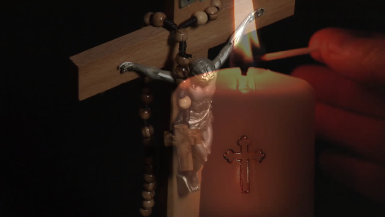 검은색 배경에 불을 켜는 손 위에 십자가의 애니메이션