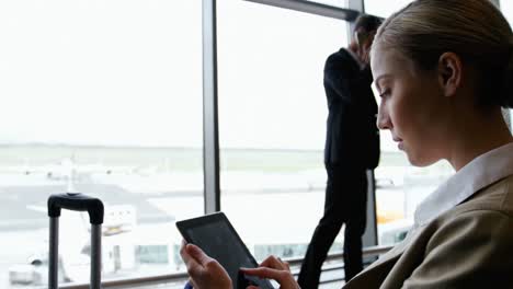businesswoman using digital tablet and smiling at airport
