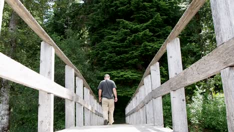 man on wooden dock on a lake walking in to the forest