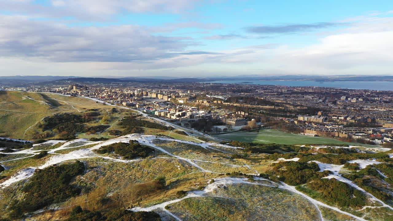 Aerial sweeping shot over a snowy Arthur's seat in Edinburgh on a crisp winters day