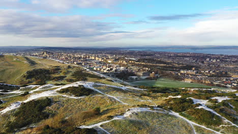 Toma-Aérea-Sobre-Un-Asiento-De-Arthur-Cubierto-De-Nieve-En-Edimburgo-En-Un-Día-De-Invierno-Fresco