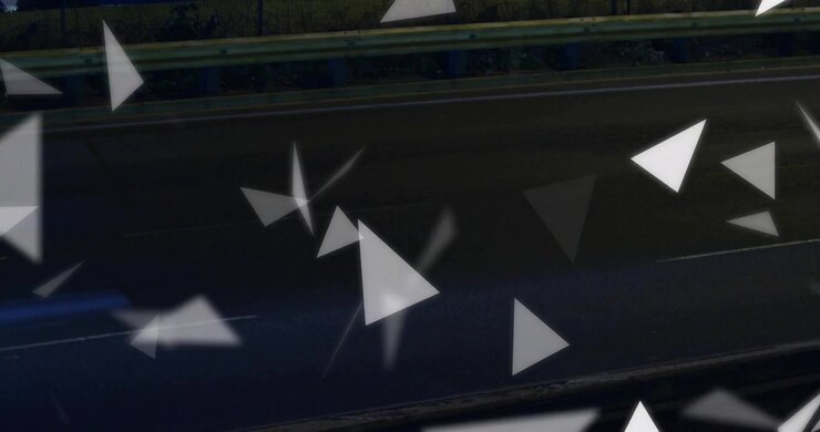 Particelle triangolari che fluttuano e ruotano su una strada buia, innescate dalla scia rossa del fanale posteriore