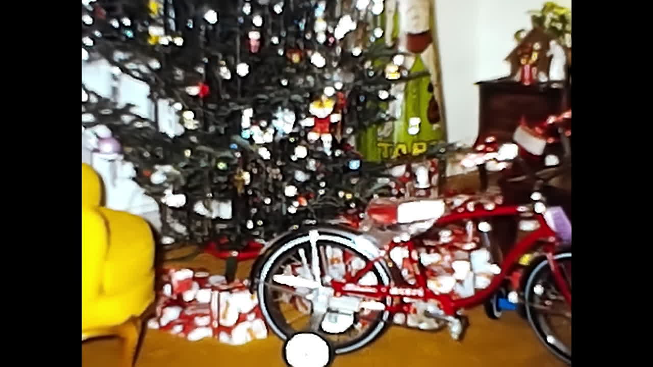 Red Bike Parked Next to Christmas Tree. CIRCA USA - 1970s: A 1970s video archive from the USA showing a red bike parked next to a festive Christmas tree.