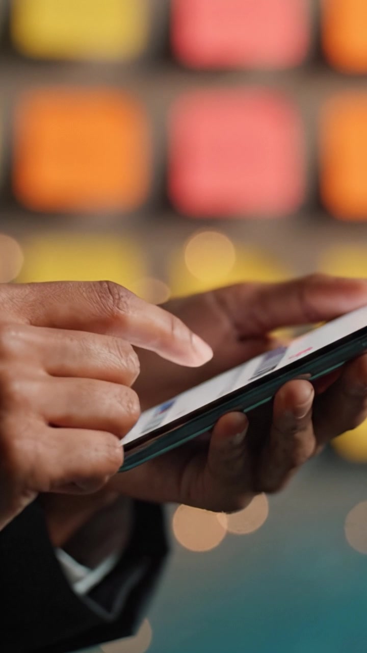 Close-Up of Hands Using a Smartphone, Featuring Touchscreen Interaction and Colorful Background Elements, Capturing the Modern Digital Communication Experience.