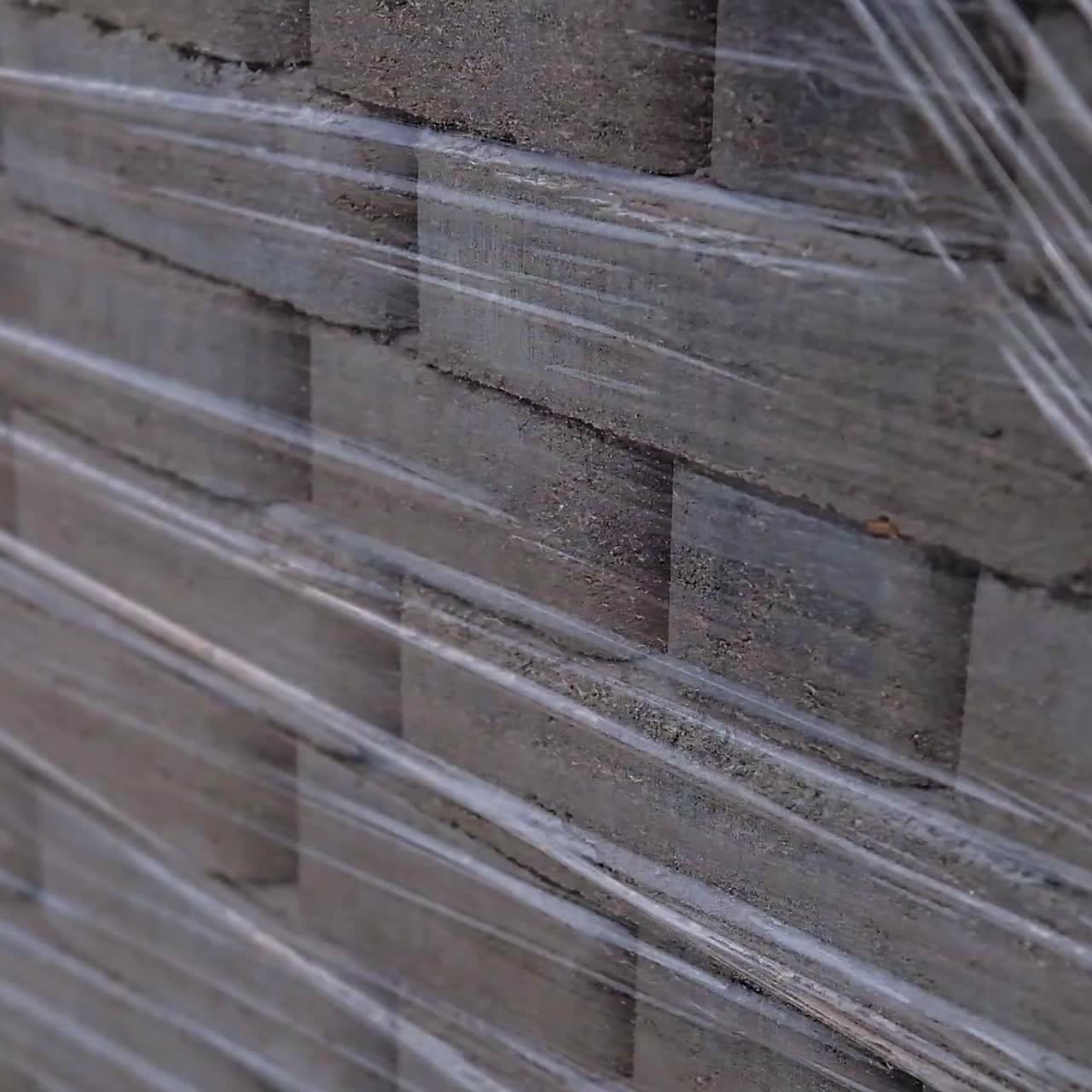 Stacked pack of grey brick for pavement. New pile of construction materials protected by cellophane. Close up