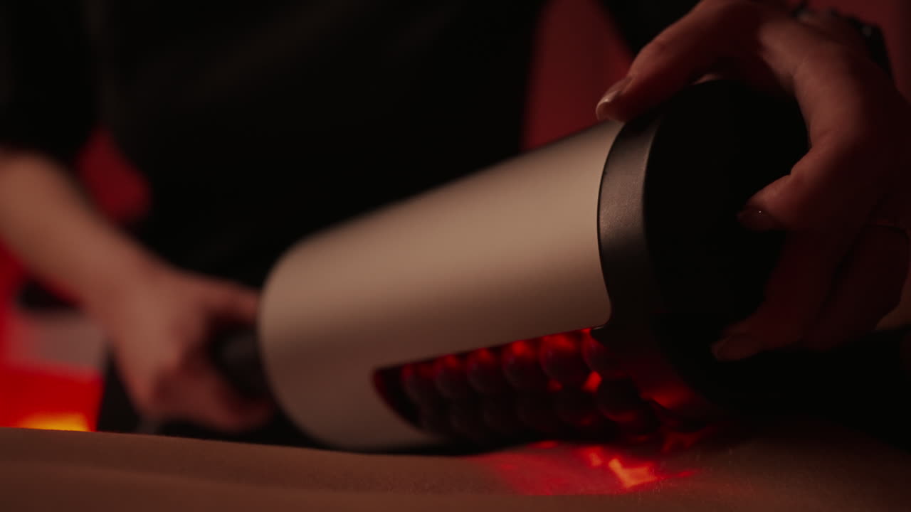 женщина получает массаж с помощью устройства для терапии красным светом