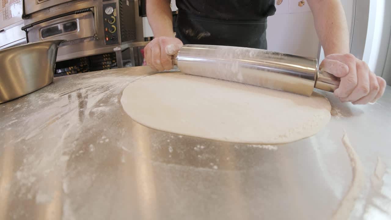 итальянский шеф-повар пиццы формирует тесто на мучной поверхности и разворачивает тесто