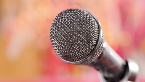 Microphone-on-stage-against-a-blurry-light-,blurry-background.