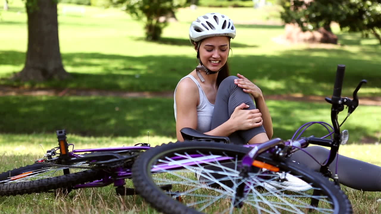 chica en forma tocando su rodilla lesionada después de un accidente de bicicleta
