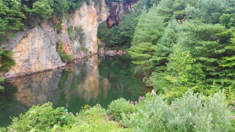 4k drone video of beautiful mountain pond surrounded by trees at emerald village near little switzerland, nc on summer day-4