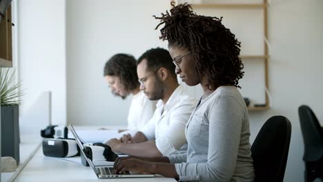 Focused-young-woman-with-dreadlocks-typing-on-laptop