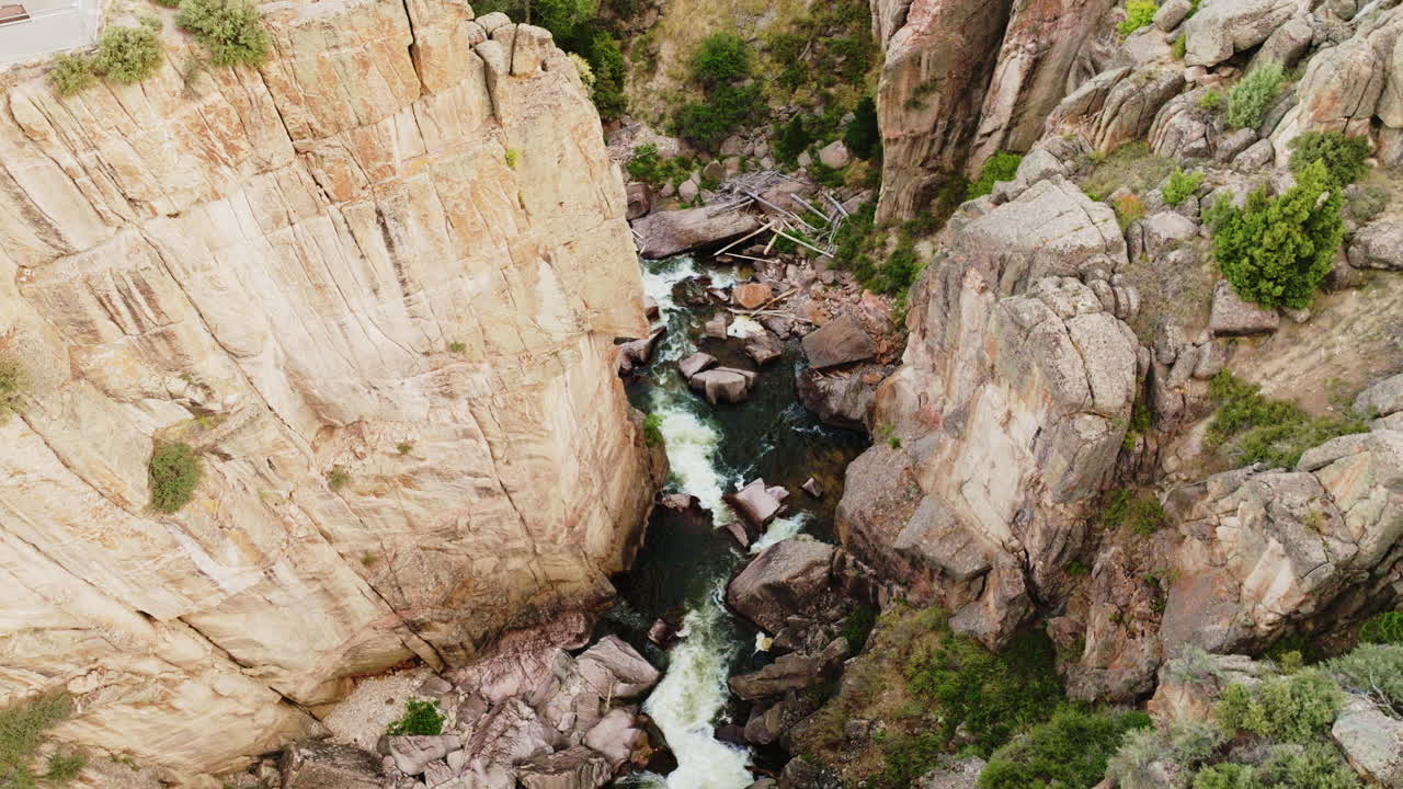 Overhead drone shot gradually angling down to showcase a river meandering through a dramatic western canyon.